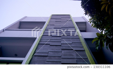 Looking up to a modern apartment building with green tiled roof. Looking up to a modern apartment building with green tiled roof. 138311106
