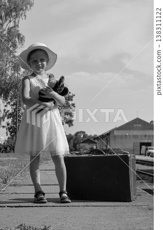 Young girl with teddy bear and vintage suitcase on train station platform 138311122