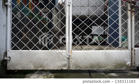 Old white metal gate on the side of the road. Mossy and grunge texture. Old white metal gate on the side of the road. Mossy and grunge texture. 138311165