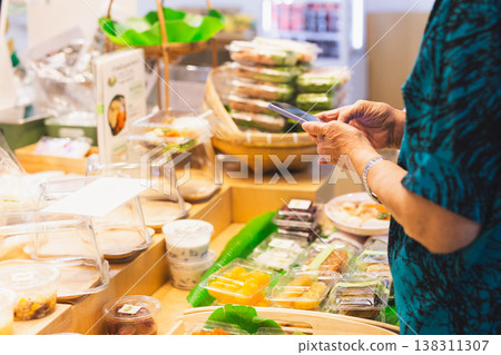 Senior woman using a smartphone paying bill at store market. Senior woman using a smartphone paying bill at store market. 138311307