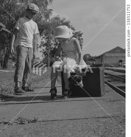 Children with vintage suitcase waiting at a train station platform on a sunny day Children with vintage suitcase waiting at a train station platform on a sunny day 138311753