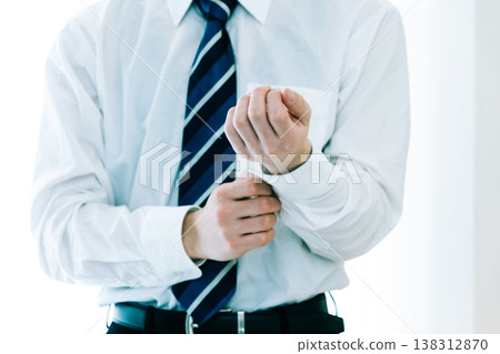A businessman fastening the buttons on his sleeves. A businessman fastening the buttons on his sleeves. 138312870