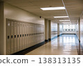 Empty school hallway with rows of beige metal lockers and bright fluorescent lighting 138313135
