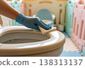 Hand wearing blue glove cleaning toilet seat with wet wipe for hygiene and sanitization 138313137