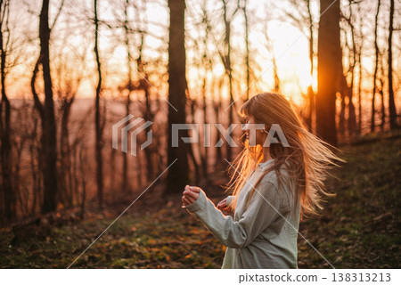 Carefree Young Woman with Blowing Hair in Forest 138313213