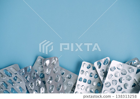 Empty silver blister packs form border at bottom of blue background. Non-recyclable medical waste, plastic pollution in healthcare, eco-friendly pharmacy. Empty silver blister packs form border at bottom of blue background. Non-recyclable medical waste, plastic pollution in healthcare, eco-friendly pharmacy. 138313258