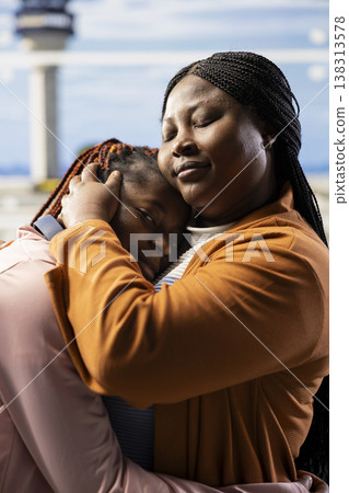 Sad mother saying farewell to their teenage daughter at airport lounge, offering guidance before boarding airplane alone. Emotional family bond with young girl traveling as foreign student. Sad mother saying farewell to their teenage daughter at airport lounge, offering guidance before boarding airplane alone. Emotional family bond with young girl traveling as foreign student. 138313578