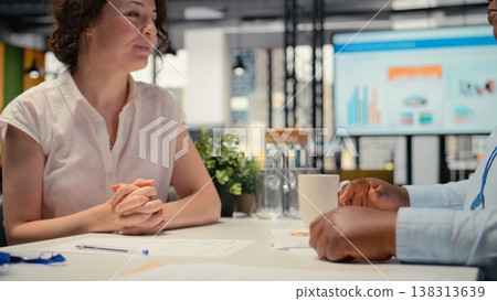HR manager and woman applicant share handshake after successful discussion, confirming the start of the work collaboration. Agreement to terms of the contract within onboarding process. Camera A. 138313639