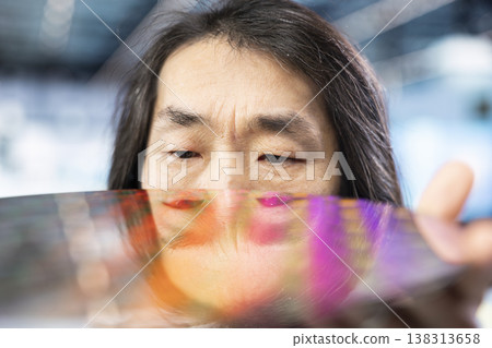Asian man holding silicon wafer, producing advanced electronic hardware in manufacturing plant. Tech industry leader looking at integrated circuits semiconductor substrate, close up shot Asian man holding silicon wafer, producing advanced electronic hardware in manufacturing plant. Tech industry leader looking at integrated circuits semiconductor substrate, close up shot 138313658