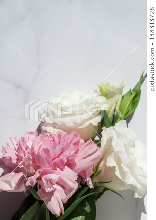 A delicate bouquet of flowers with pink carnations and white eustoma on a marble background. A delicate bouquet of flowers with pink carnations and white eustoma on a marble background. 138313728