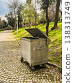 Open metal dumpster on park pathway under trees in bright daylight. 138313749