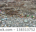 A littered pebble beach with rough waves and accumulations of debris and plastic. 138313752