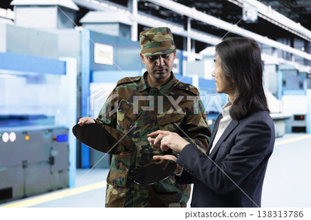 Army man talks with senior manager about using silicon wafer supply chain for national security purposes. Military soldier and Asian director reviewing strategic microelectronics factory production Army man talks with senior manager about using silicon wafer supply chain for national security purposes. Military soldier and Asian director reviewing strategic microelectronics factory production 138313786