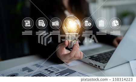 Business Innovation Concept with Light Bulb Symbolizing Ideas and Growth in Modern Office Environment with Charts and Laptop Ledger Business Innovation Concept with Light Bulb Symbolizing Ideas and Growth in Modern Office Environment with Charts and Laptop Ledger 138314223