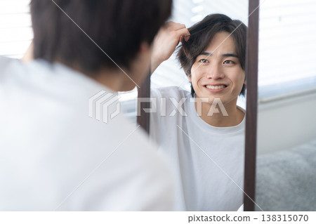 一位年輕男子正在窗邊進行日常護膚。 138315070