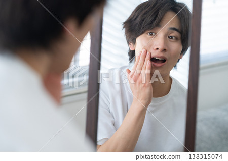 一位年輕男子正在窗邊進行日常護膚。 138315074