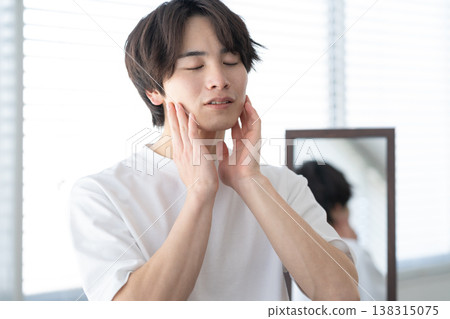 A young man doing his skincare routine by the window. 138315075