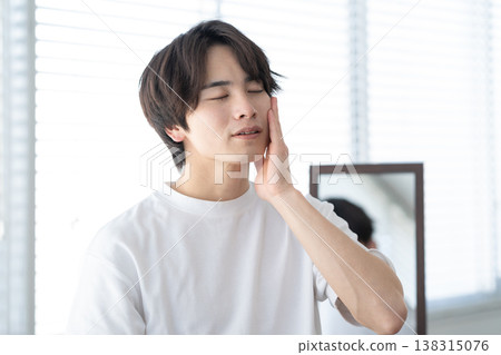 A young man doing his skincare routine by the window. A young man doing his skincare routine by the window. 138315076