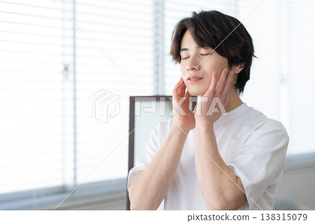 A young man doing his skincare routine by the window. A young man doing his skincare routine by the window. 138315079