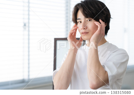 A young man doing his skincare routine by the window. A young man doing his skincare routine by the window. 138315080