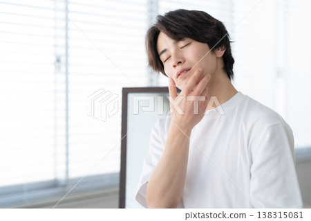A young man doing his skincare routine by the window. 138315081