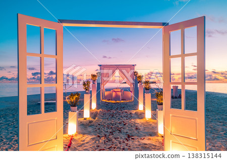 Fantastic beach dinner setting with candles, floral decorations, and elegant doors, romantic wedding couple honeymoon anniversary, artistic destination dining background 138315144