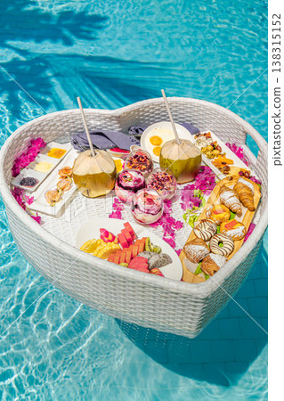 Luxury resort swimming pool close-up with floating breakfast heart shape tray, romantic couple honeymoon anniversary tropical vacation background 138315152