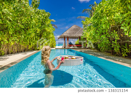 Luxury resort swimming pool with floating breakfast tray in heart shape, blonde woman relaxing, romantic honeymoon vacation tropical beach background 138315154