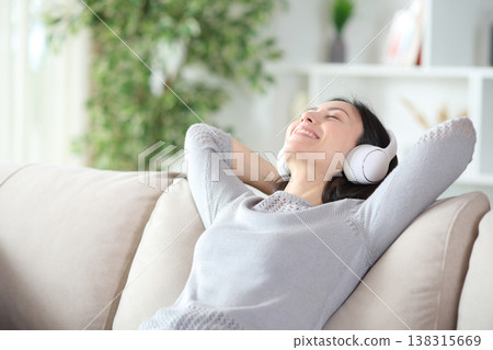 Happy asian woman wearing wireless headphone relaxing at home Happy asian woman wearing wireless headphone relaxing at home 138315669