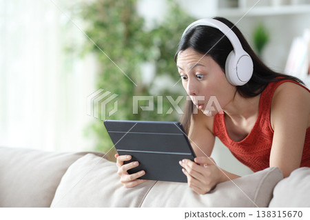Surprised asian woman checking media content on tablet 138315670
