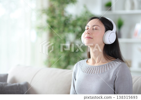 Asian woman wearing headphone breathing listening audio guide Asian woman wearing headphone breathing listening audio guide 138315693