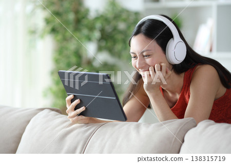 Happy asian woman enjoying watching online videos at home Happy asian woman enjoying watching online videos at home 138315719