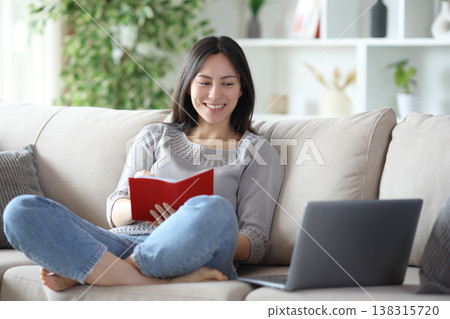 Happy asian woman holding agenda and checking computer 138315720