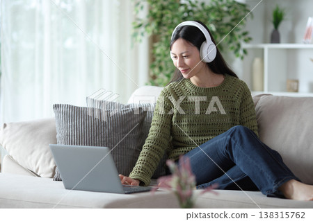 Asian woman wearing headphone checking computer 138315762