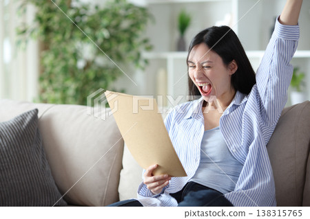Excited asian woman checking document and celebrating Excited asian woman checking document and celebrating 138315765