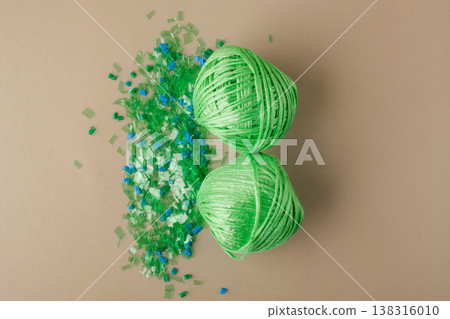Green polyester yarn made from recycled plastic on a pile of microplastic flakes symbolizes sustainability, circular economy, and environmentally friendly production Green polyester yarn made from recycled plastic on a pile of microplastic flakes symbolizes sustainability, circular economy, and environmentally friendly production 138316010