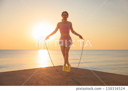 Fit woman jumping rope at the beach during summer vacation Fit woman jumping rope at the beach during summer vacation 138316524
