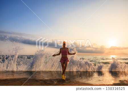 Fit woman jumping rope at the beach during summer vacation Fit woman jumping rope at the beach during summer vacation 138316525
