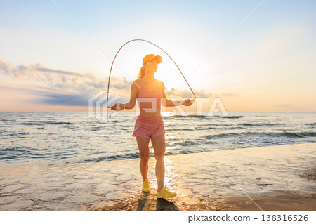 Fit woman jumping rope at the beach during summer vacation Fit woman jumping rope at the beach during summer vacation 138316526