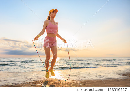 Fit woman jumping rope at the beach during summer vacation Fit woman jumping rope at the beach during summer vacation 138316527
