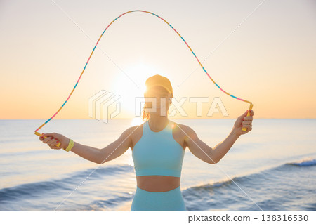 Fit woman jumping rope at the beach during summer vacation Fit woman jumping rope at the beach during summer vacation 138316530