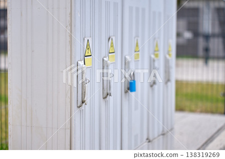 Row of outdoor electrical cabinets with warning signs and lock 138319269
