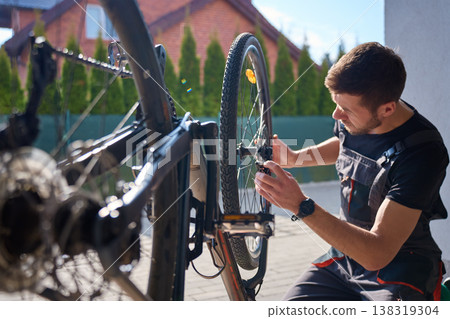 Bike mechanic repairing bicycle wheel in home garage Bike mechanic repairing bicycle wheel in home garage 138319304