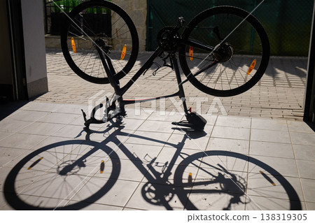 Bicycle upside down in garage with shadow on tiled floor Bicycle upside down in garage with shadow on tiled floor 138319305