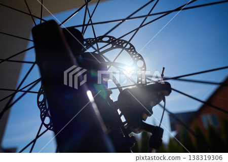 Close up of bicycle disc brake and spokes against sun Close up of bicycle disc brake and spokes against sun 138319306