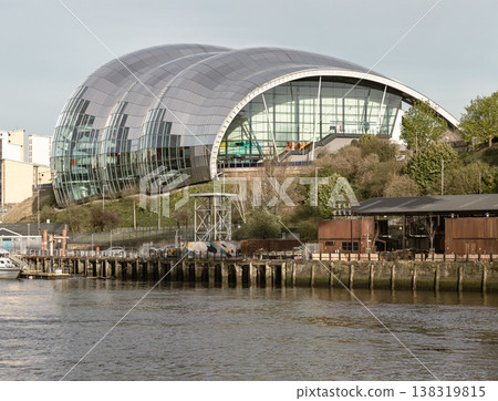 The shimmering, undulating curves of The Glasshouse International Centre for Music (Sage Gateshead) dominate the horizon, its mirrored stainless steel and glass facade reflecting the soft light. This 138319815