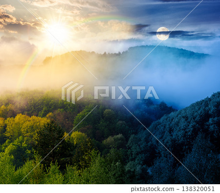 mountain landscape with cold fog. day and night time change concept. low clouds over the forested hill with sun and moon. outdoor scenery in spring for remote highland ecotourism. wonderful greenery 138320051