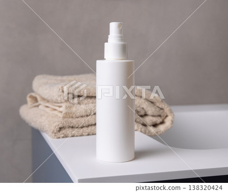 White spray cosmetic bottle near bath towel in beige bathroom, cosmetic mockup 138320424