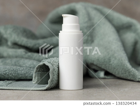 White pump cosmetic bottle mockup near sage green bath towel on stone. Unbranded blank packaging 138320434