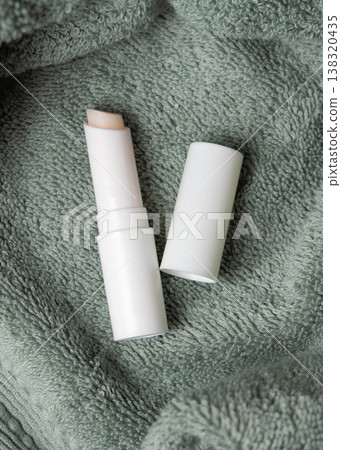 White opened lip balm stick mockup with a lid on sage green bath towel, unbranded packaging 138320435